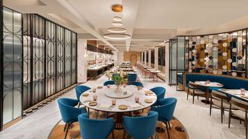 A modern dining area with a round table, blue chairs, and a decorative wall with circular patterns.