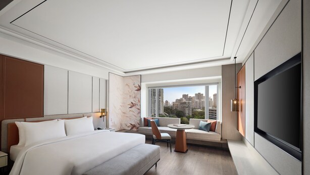 A modern hotel room with a large bed, a sofa, a dining table, and a TV. - Radisson Mumbai Goregaon (Mumbai)