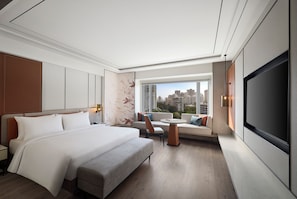 A modern hotel room with a large bed, a sofa, a dining table, and a TV. - Radisson Mumbai Goregaon (Mumbai)
