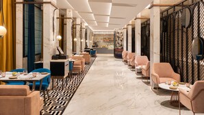 A modern hotel lobby with a central seating area, a bar, and a view into the dining area. - Radisson Mumbai Goregaon (Mumbai)