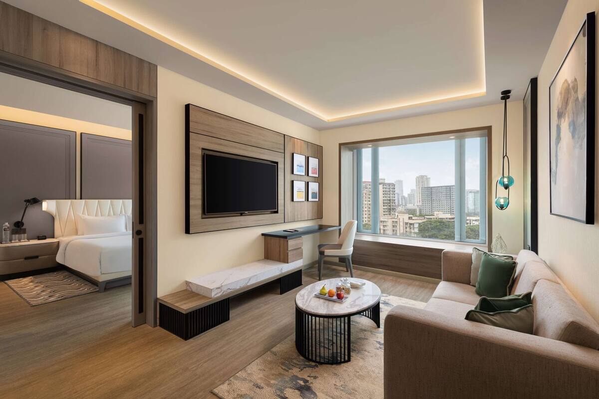 A modern living room with a bed, sofa, TV, and city view.