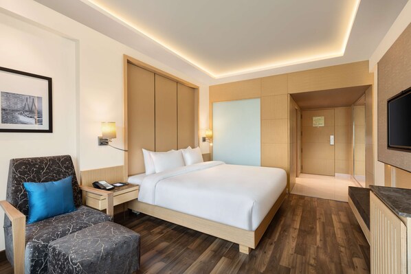 A modern hotel room with a large bed, a desk, a chair, and a television. - Radisson Mumbai Goregaon (Mumbai)