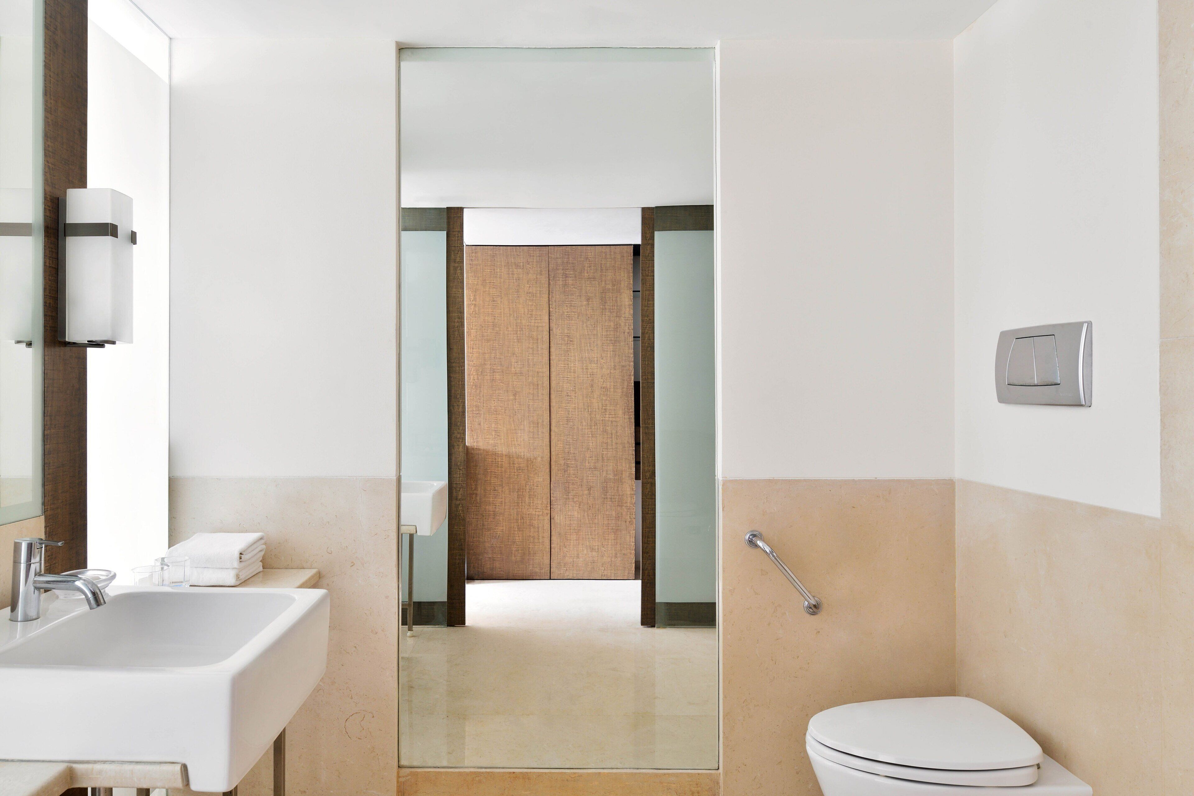Ein modernes Badezimmer mit Waschbecken, Spiegel und Toilette in Weiß.