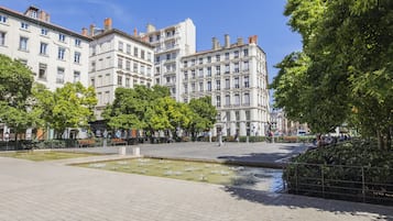 A public square with a fountain, surrounded by historic buildings and trees.