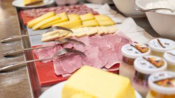 Un bufé con diversos quesos, embutidos y salsas.