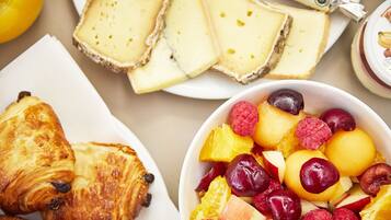 A breakfast setting with croissants, cheese, and a fruit bowl.