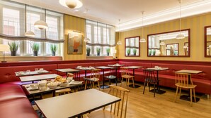 Un restaurante con asientos tapizados en rojo, mesas de madera y lámparas colgantes.