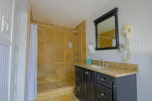 Enjoy a refreshing shower in this bathroom with a walk-in shower, sink, and mirror.