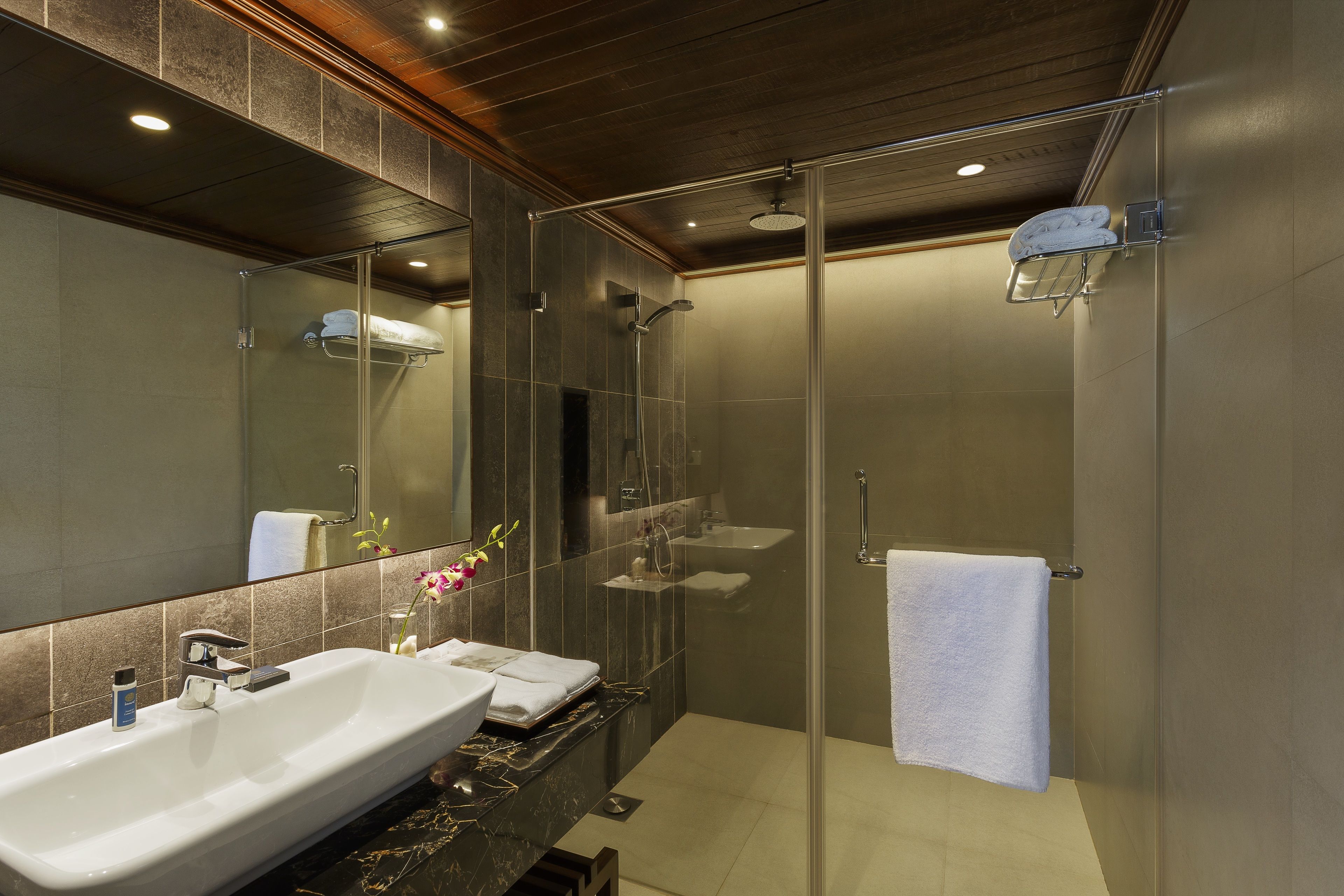 Un baño moderno con ducha de vidrio, lavamanos grande y espejo.
