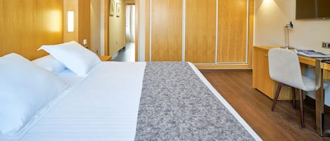 A hotel room with a bed, a desk, a chair, and a wardrobe.