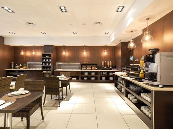 Cocina moderna con comedor, equipada con cafetera y diversos alimentos.