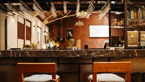 A bar area with wooden chairs, a marble counter, and hanging crystal chandeliers. - Auckland City Hotel (Auckland)