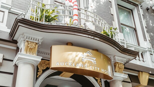 The Auckland City Hotel entrance with a sign above the doorway, columns, and a balcony with railings and plants. - Auckland City Hotel (Auckland)