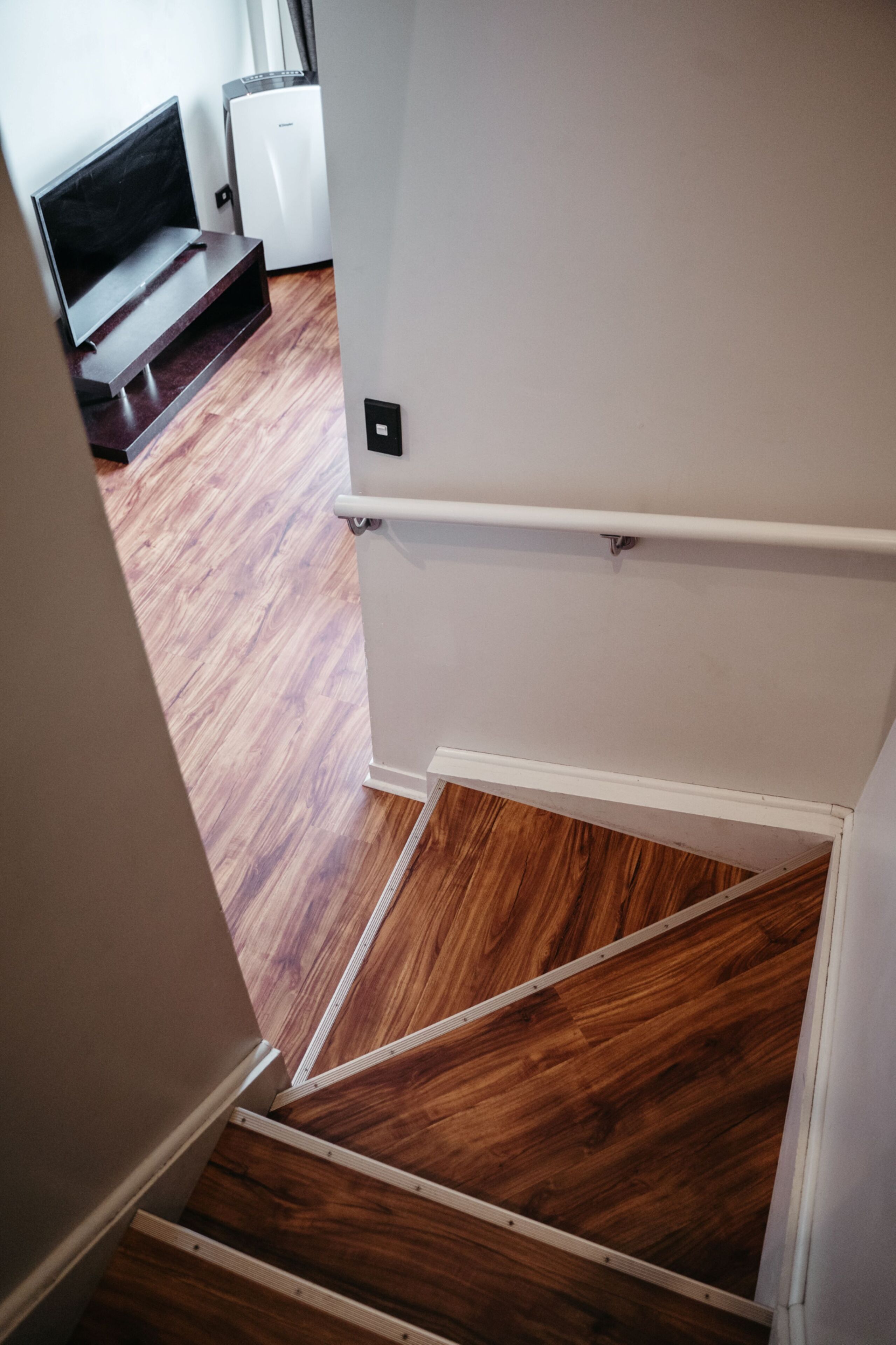 A staircase with wooden flooring leading to a room with white walls and a white door.