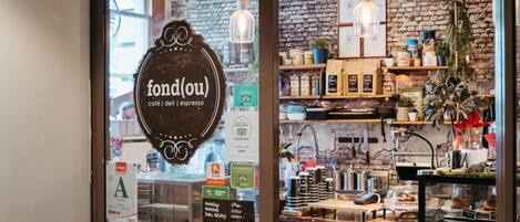 A café interior with a brick wall, wooden shelves, and a chalkboard menu.