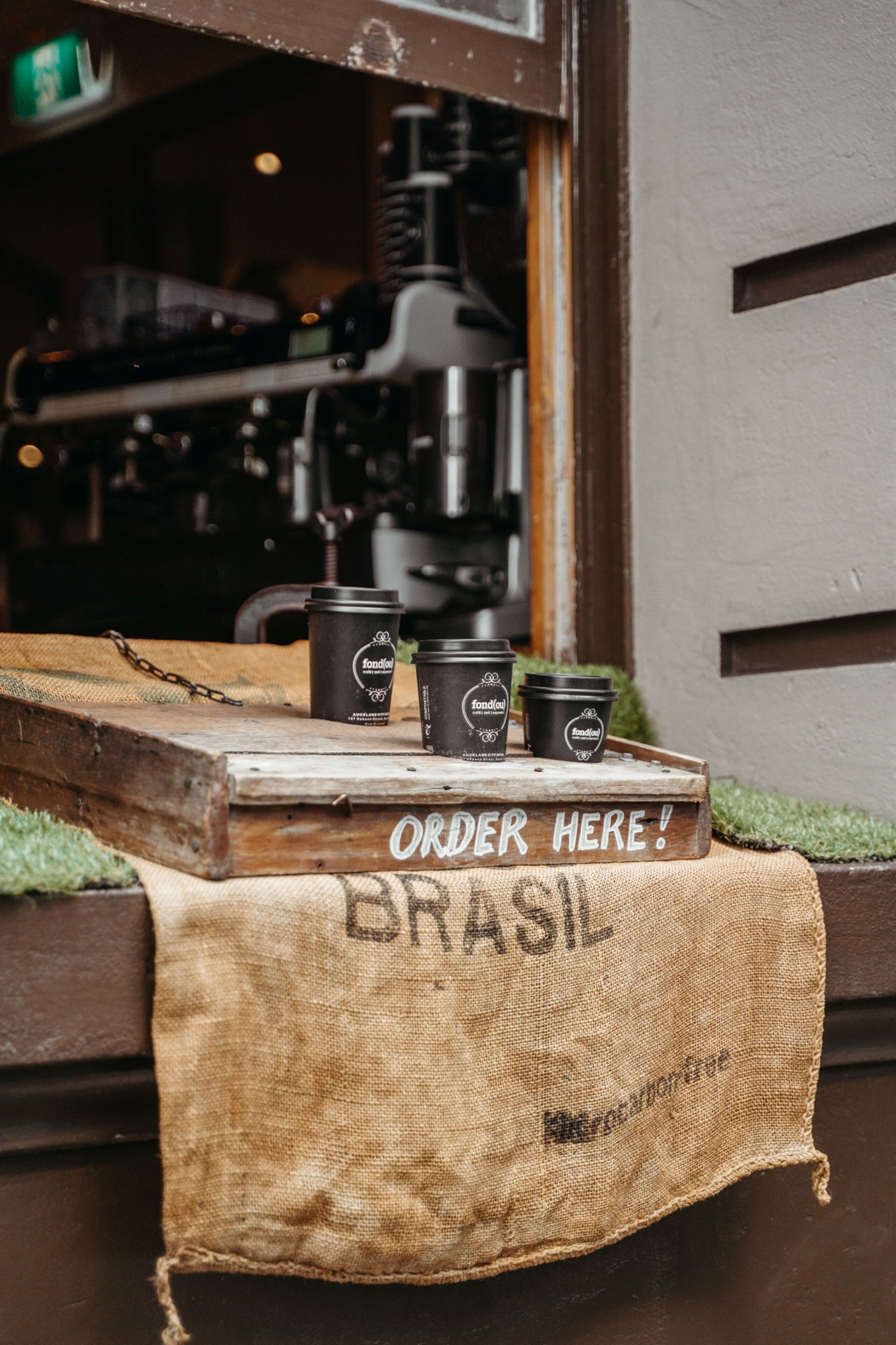 Mostrador de cafetería con tres tazas de café y un cartel que dice 