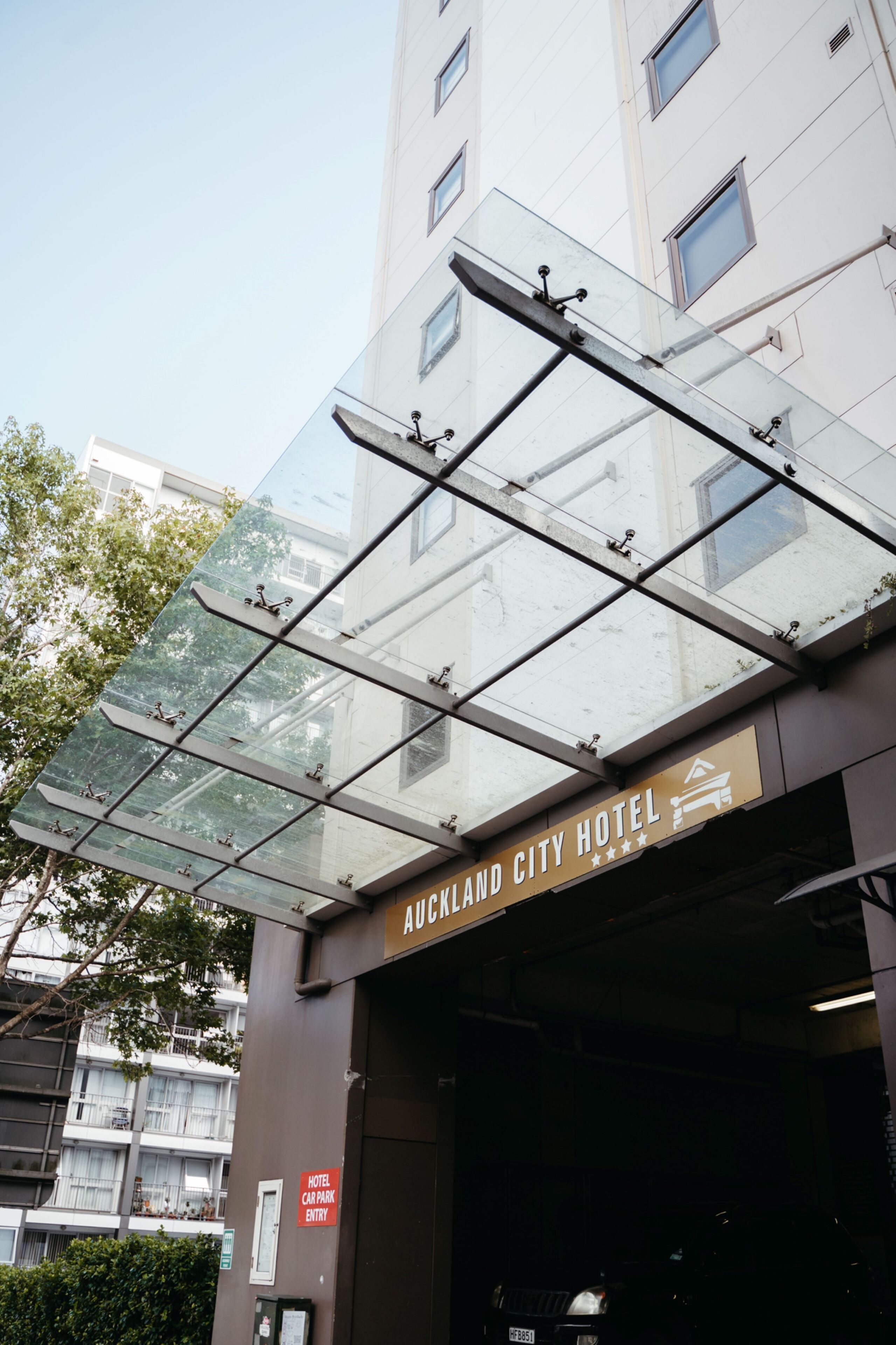 Eingang des Auckland City Hotels mit einer Glaskuppel und einem Schild, das den Zugang zu einer Parkgarage kennzeichnet.