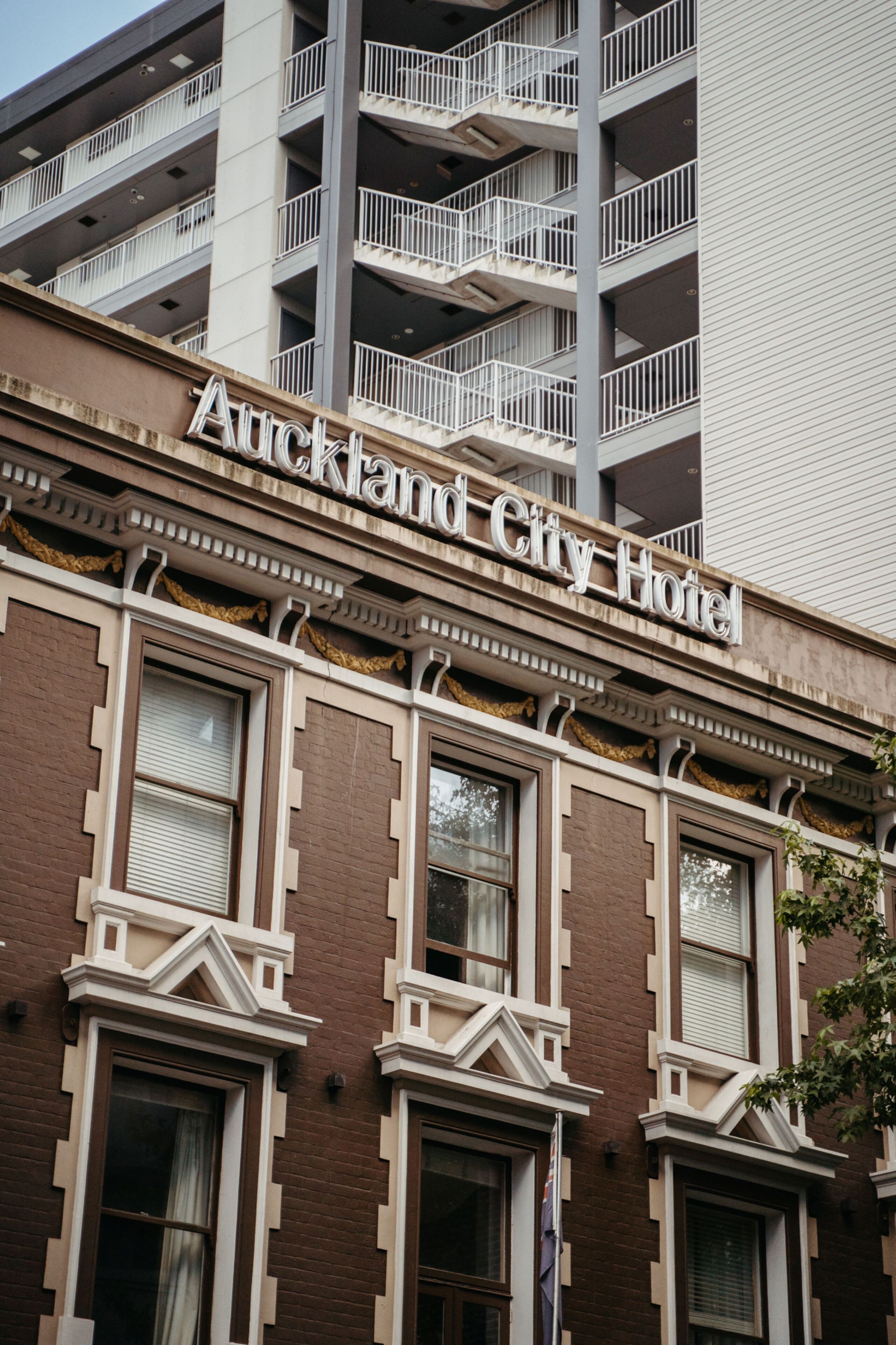 The exterior of the Auckland City Hotel with a classic architectural style, featuring multiple balconies and a prominent hotel sign.