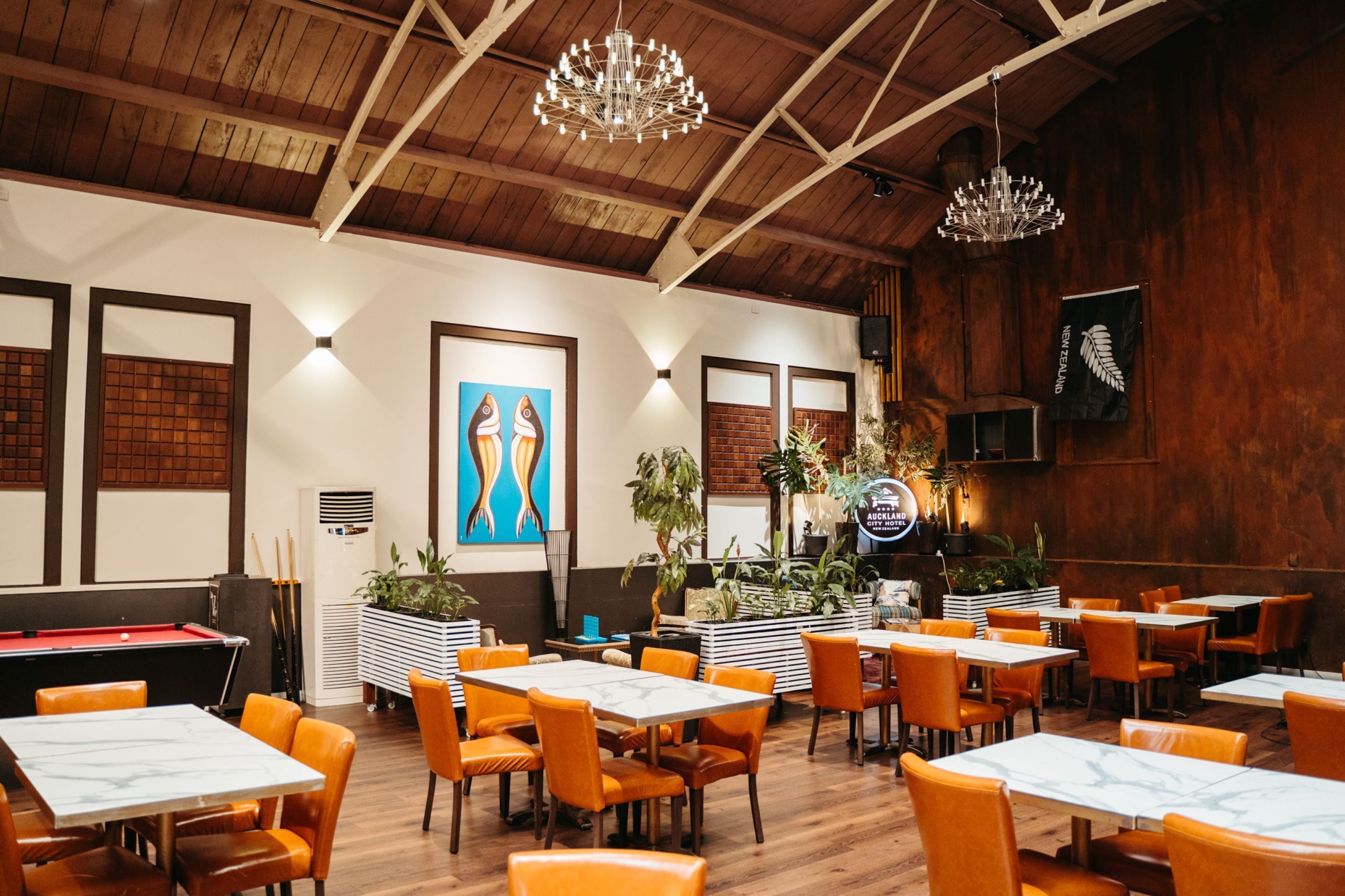 Un restaurante con techos de madera, sillas anaranjadas y una mesa de billar.