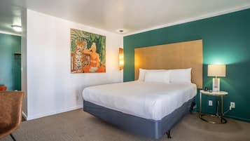 Une chambre d’hôtel avec un grand lit, un tableau au mur, une petite table avec une lampe et une chaise.