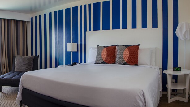 Habitación de hotel con una cama grande, un escritorio, una silla y vistas al exterior.