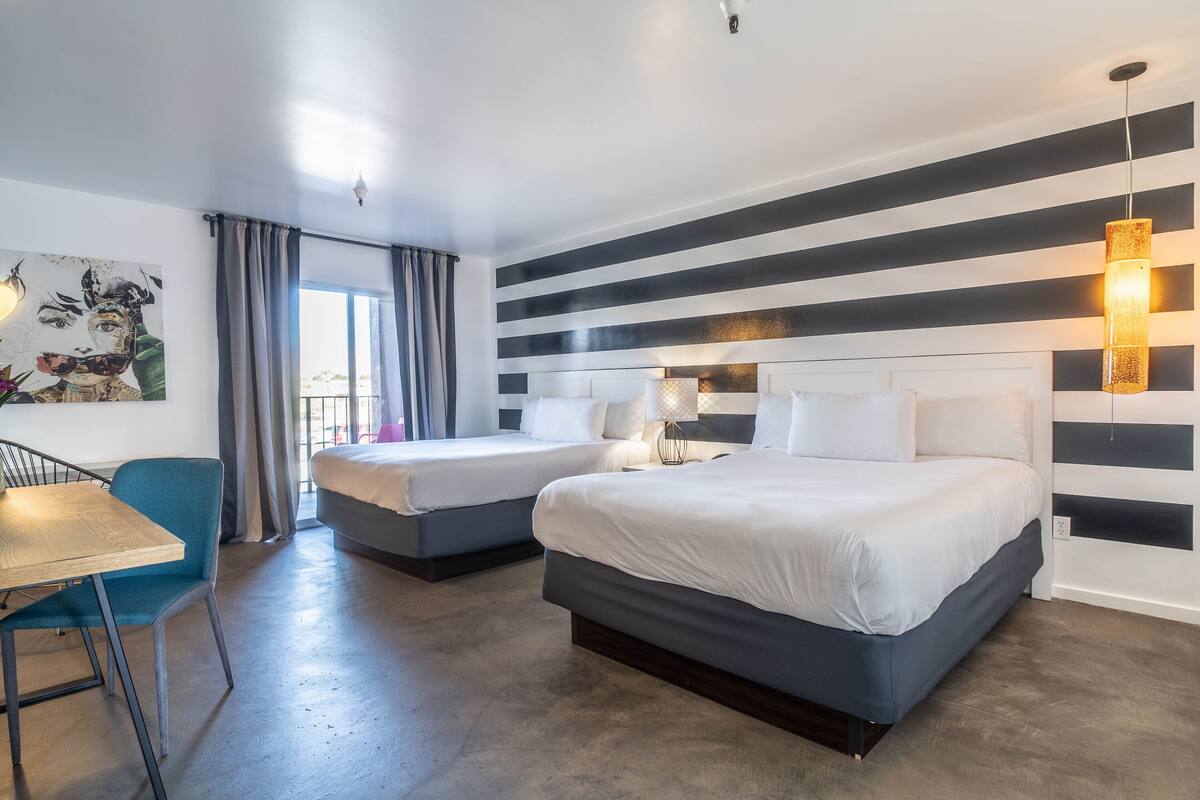 Ein Hotelzimmer mit zwei Betten, einem Esstisch und Blick ins Freie.