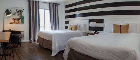 A hotel room with two beds, a desk, a chair, a TV, and a painting on the wall.
