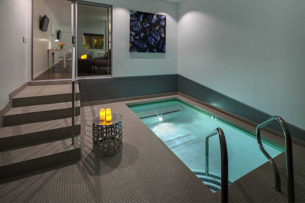 Ein moderner Innenpoolbereich mit Glaswand, Treppe und einer dekorativen Kerzenhalterung.