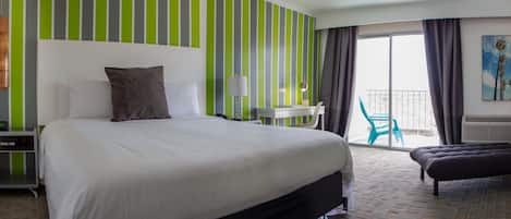 Een hotelkamer met een groot bed, een bureau, een stoel en een balkon met uitzicht.