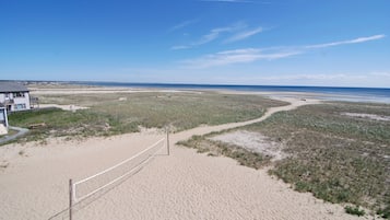 A beach with a volleyball net, a building, and a clear sky.