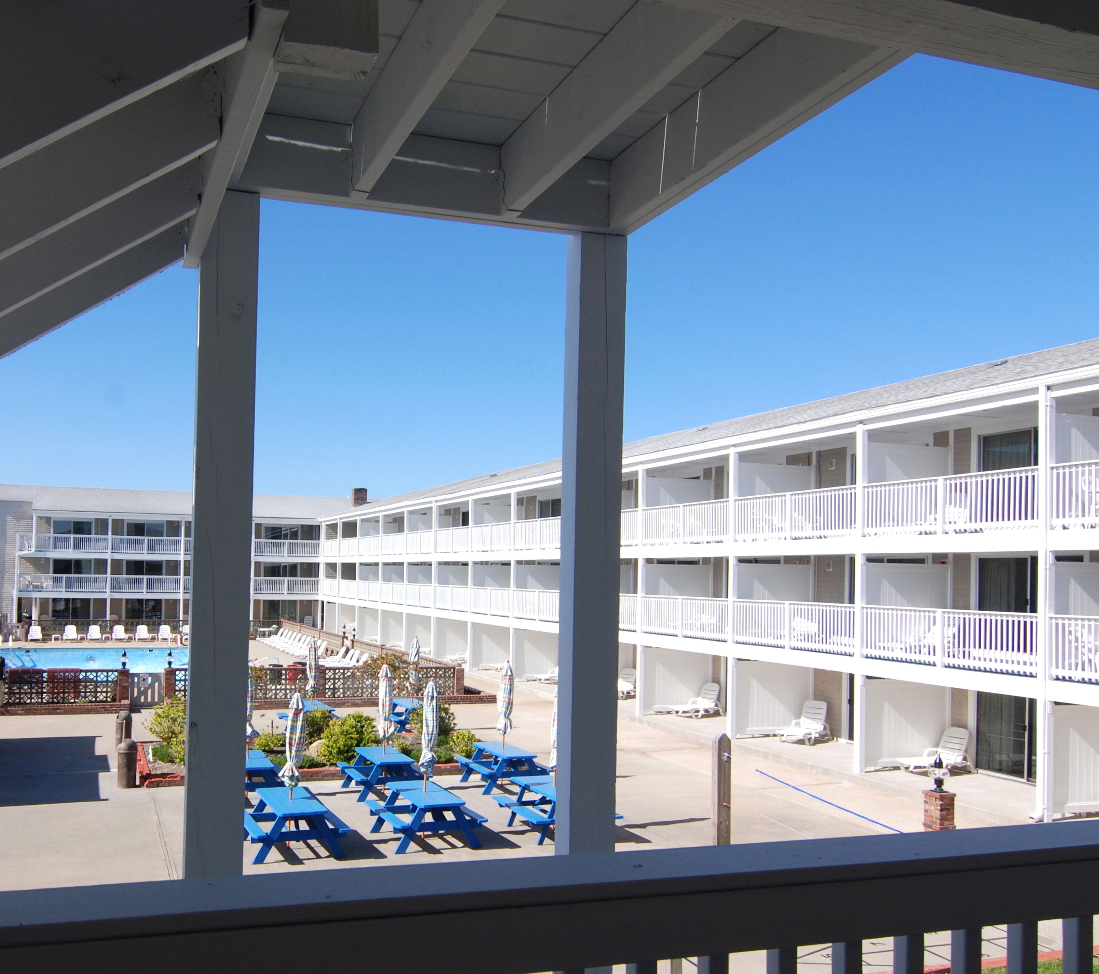 Un hôtel doté de nombreux balcons, d’un espace piscine avec des chaises longues et d’un ciel d’un bleu limpide.