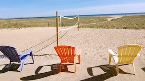 Three beach chairs on a sandy beach with a volleyball net in the background and a clear sky. - Sandcastle Resort and Club (Provincetown)
