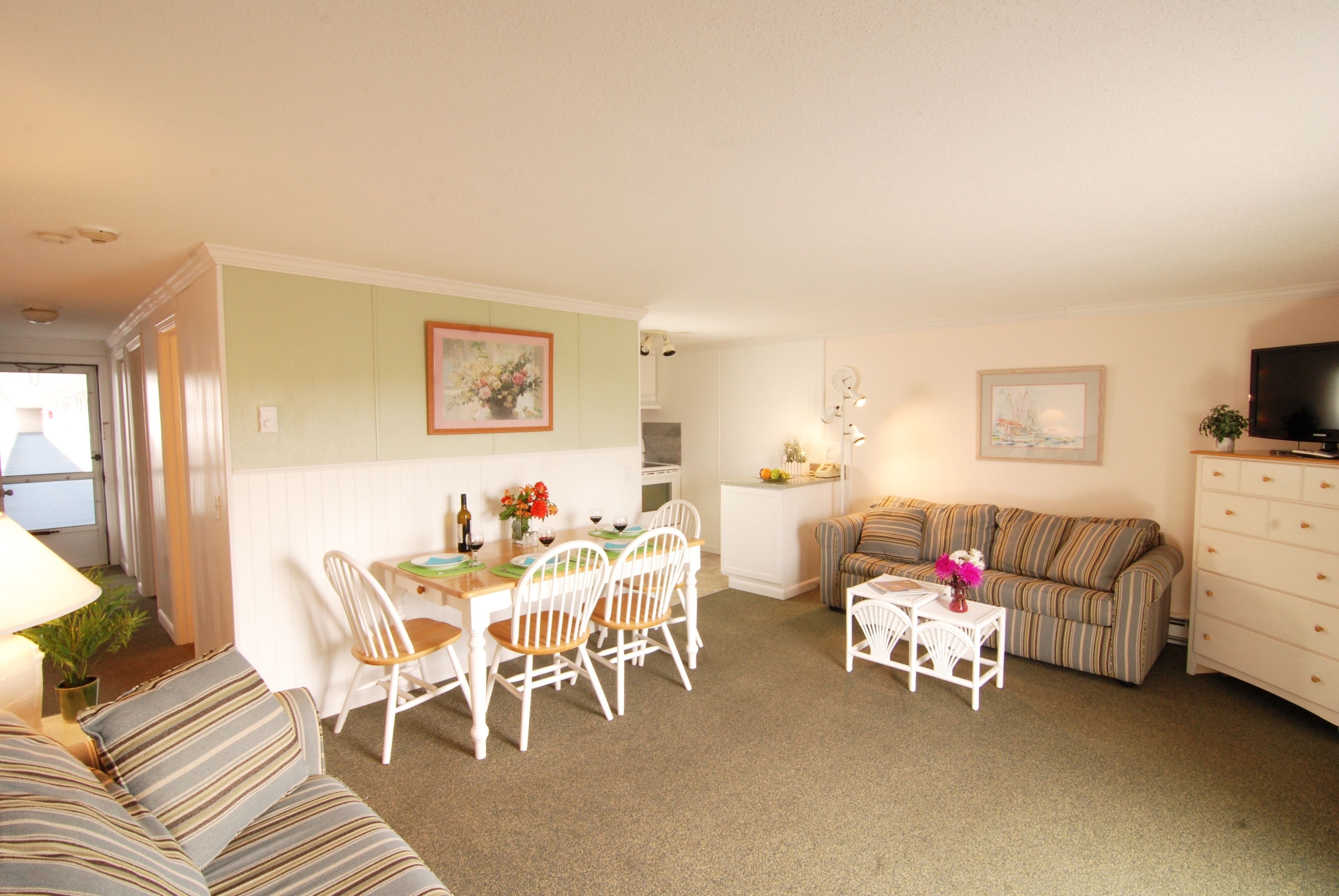 A compact living space with a dining area, a sofa, a television, and a kitchen area.