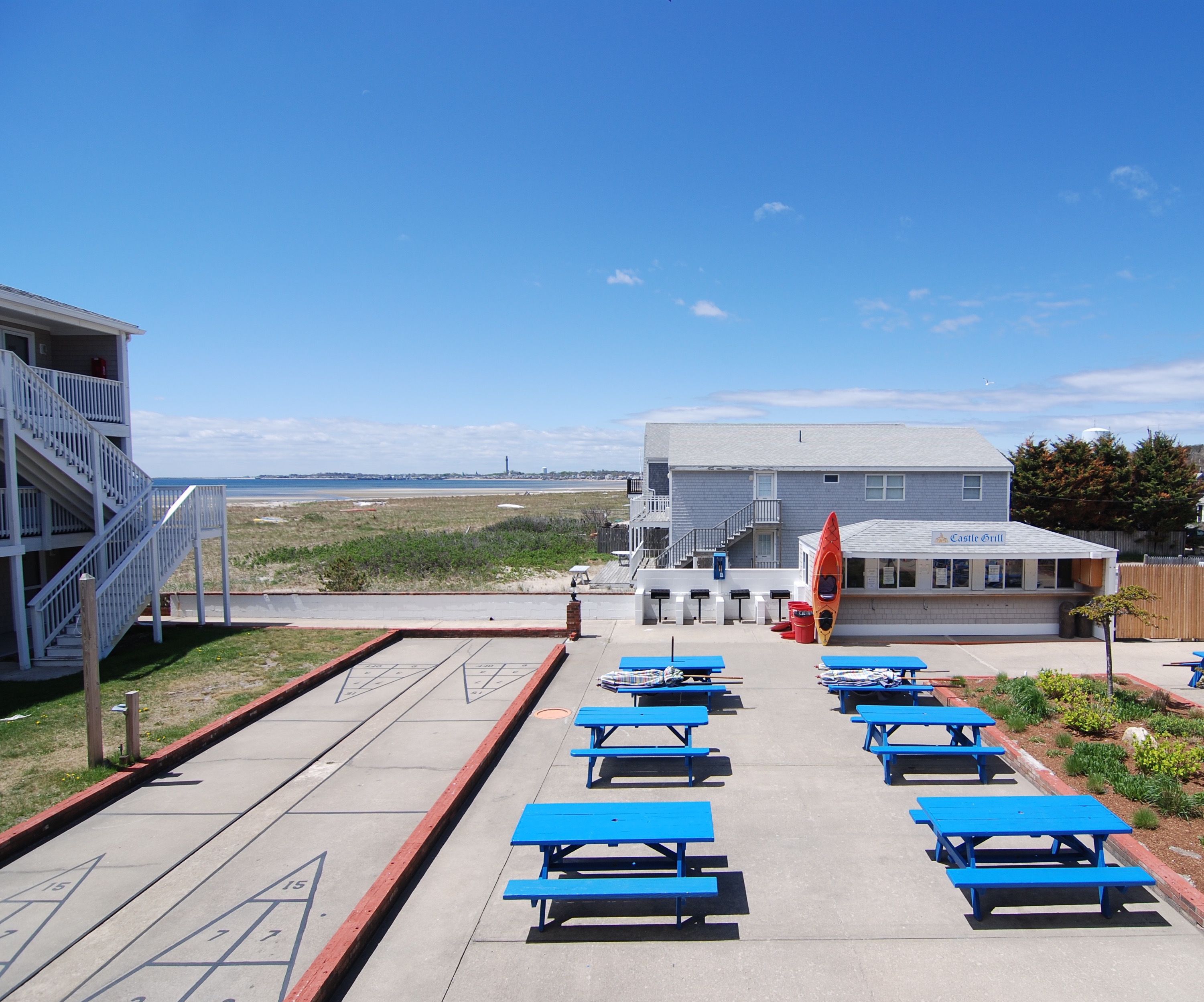 A beachside building with a dining area, picnic tables, and a view of the ocean.