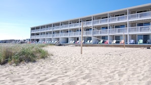 A multi-story hotel with balconies, beach chairs, and a sandy beach in the foreground. - Sandcastle Resort and Club (Provincetown)
