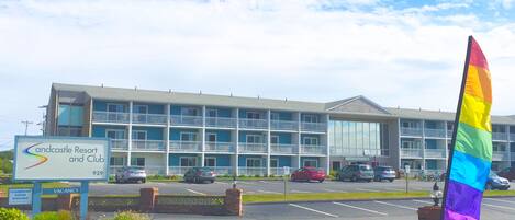 A hotel with a signboard indicating 'Sandcastle Resort and Club' and a rainbow flag.