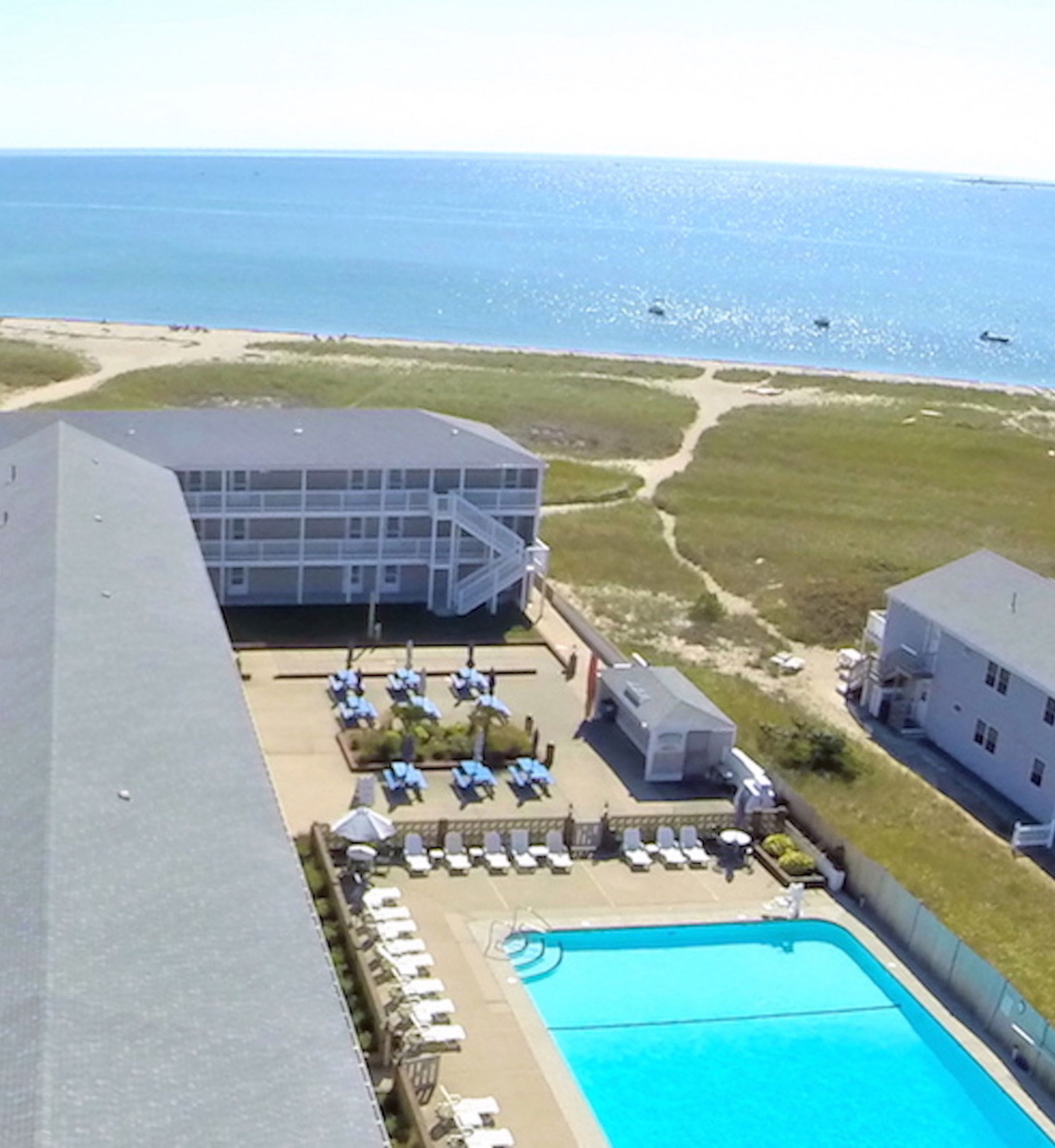 Un hotel con piscina, sdraio e vista sull'oceano.