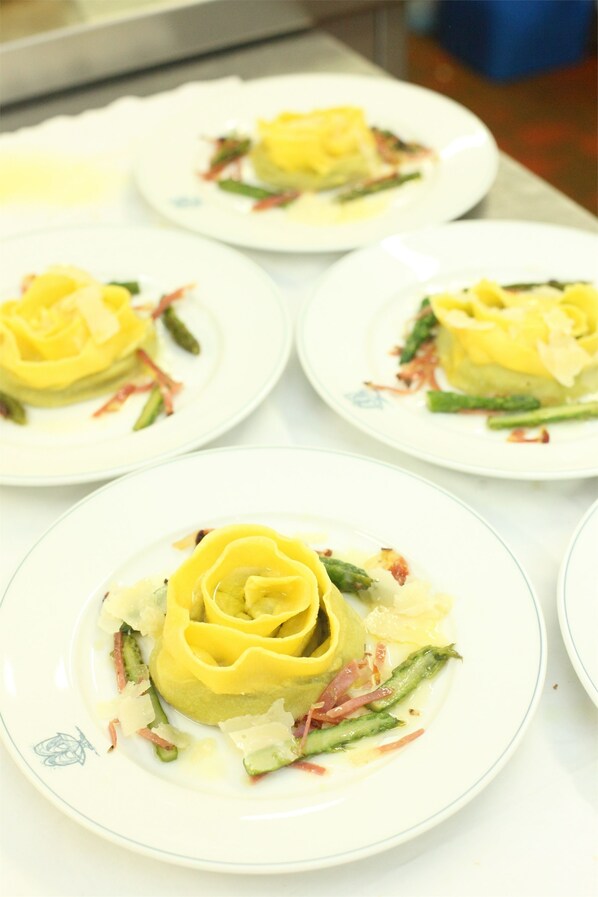 Una mesa con platos de comida, incluyendo un plato con forma de flor amarilla y verduras verdes.
