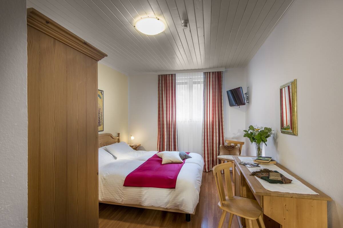 Un dormitorio con cama, escritorio y silla.
