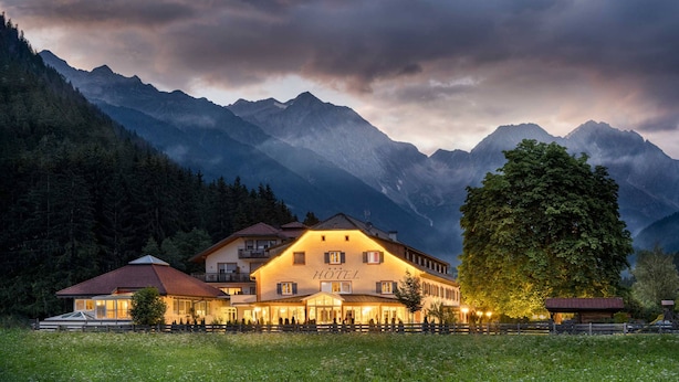Un hôtel doté d’un grand bâtiment, d’une cour clôturée et ayant des montagnes en toile de fond.