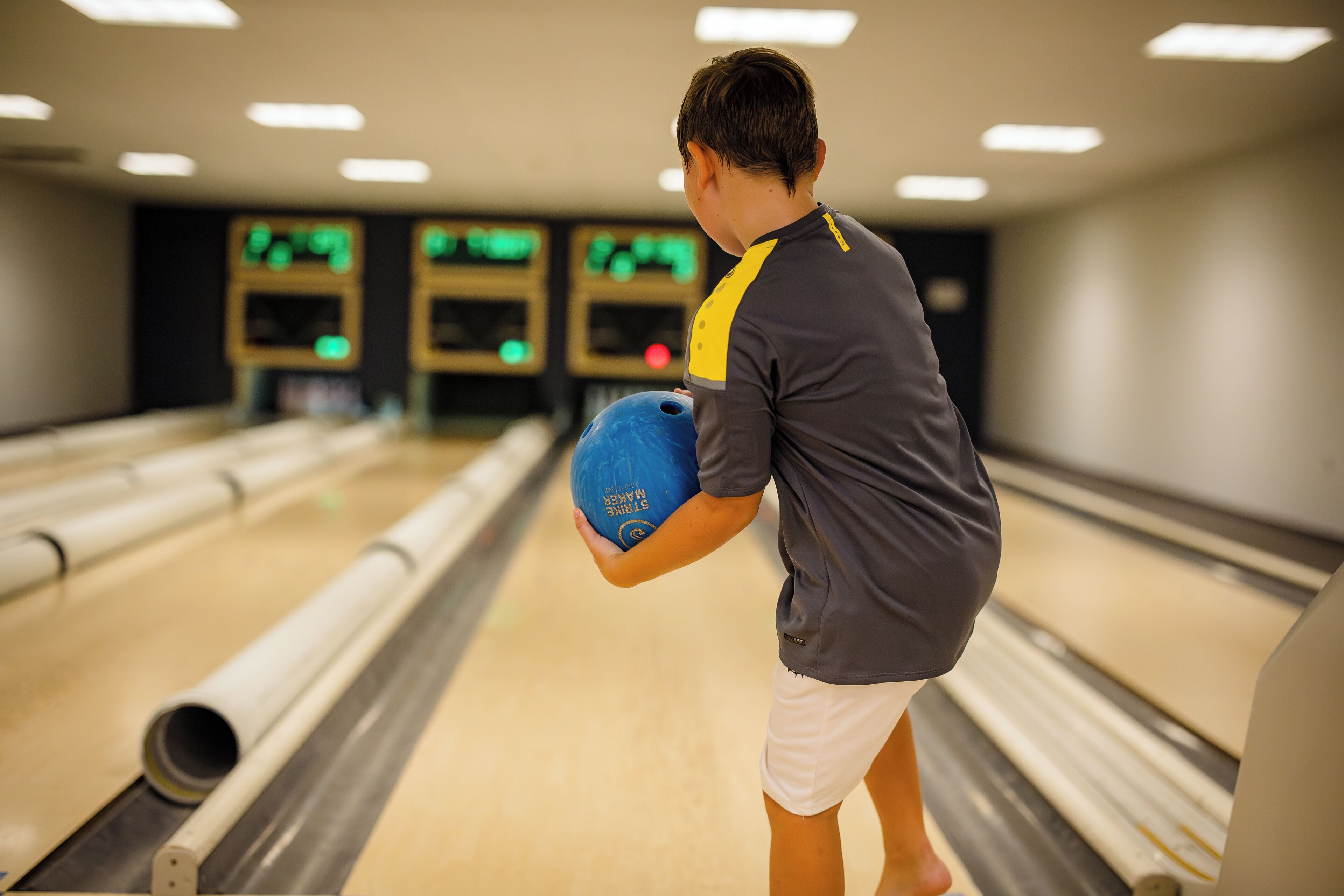 A bowling alley with lanes, a bowling ball, and a person holding a ball.