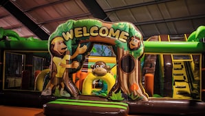 An indoor play area with a 'WELCOME' sign featuring cartoon characters, inflatable structures, and a slide. - Thermenhotel Kurz (Lutzmannsburg)