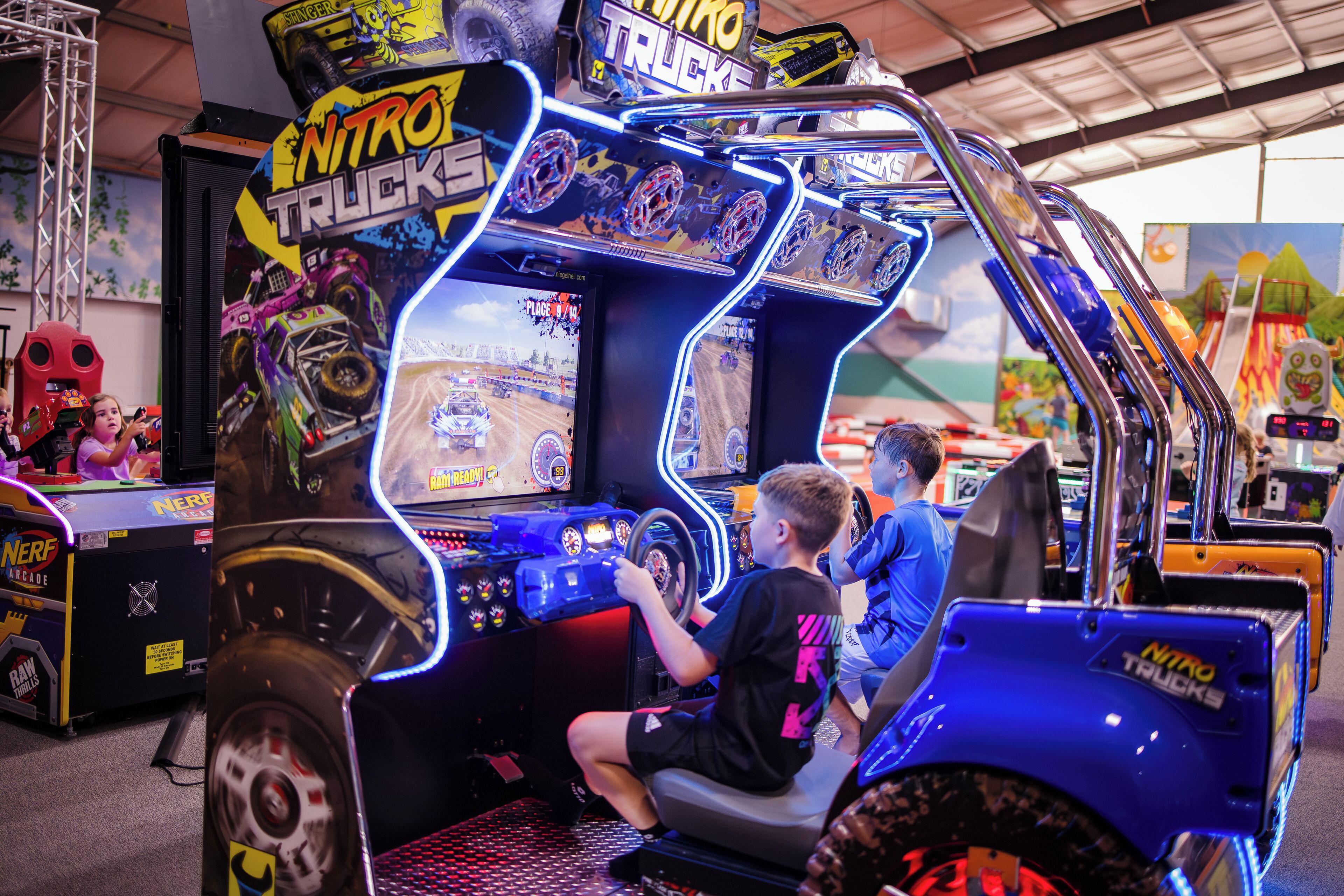 A truck-themed arcade game with neon lights and a steering wheel.