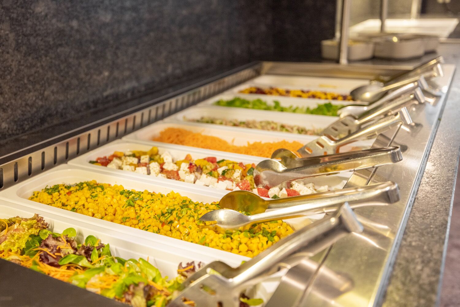 A buffet with various food options and serving utensils.