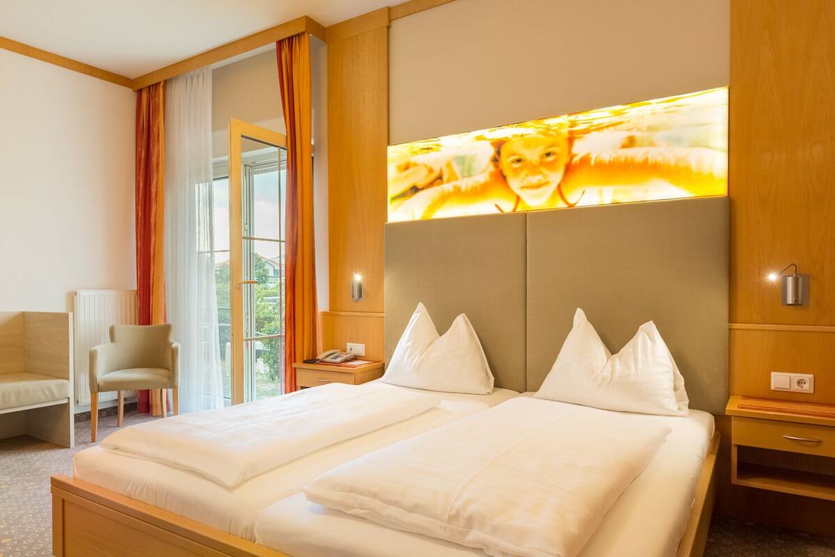 Hotellihuone, jossa on suuri sänky, työpöytä, tuoli ja ikkuna, jossa on verhot.
