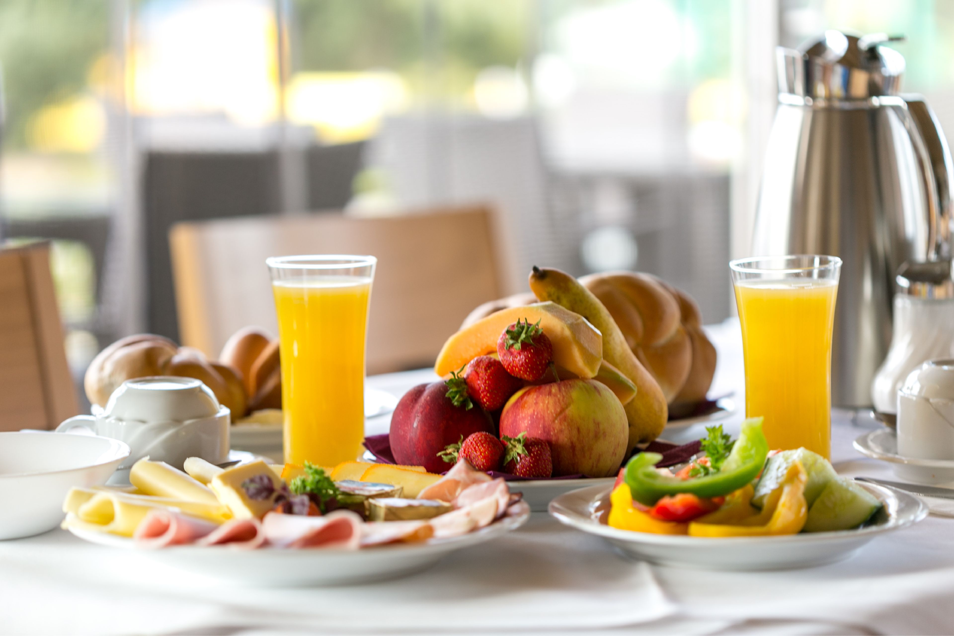 Una mesa con platos de frutas, pasteles y bebidas para el desayuno.