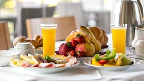 Une table dressée pour le petit-déjeuner, avec des assiettes de fruits, des viennoiseries et des boissons.