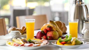 Una mesa con platos de frutas, pasteles y bebidas para el desayuno.