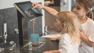 Un niño interactuando con una máquina expendedora de café, sirviendo café en una taza.