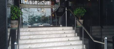 A set of marble stairs leading to a lobby area with glass doors and a sign above the entrance.